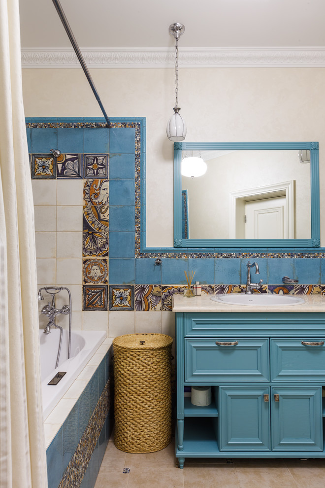 На фото: главная ванная комната в средиземноморском стиле с бирюзовыми фасадами, разноцветной плиткой, бежевыми стенами, накладной раковиной, бежевым полом и бежевой столешницей с