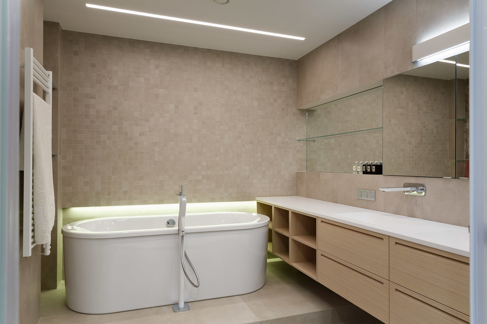 Modelo de cuarto de baño actual con bañera exenta, baldosas y/o azulejos beige y lavabo integrado