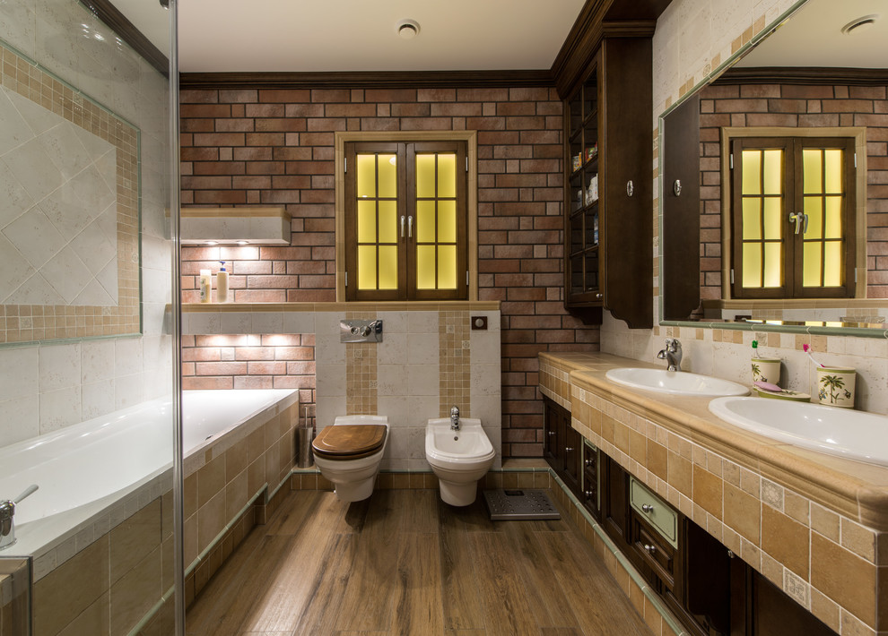 Foto på ett mellanstort vintage badrum, med luckor med upphöjd panel, skåp i mörkt trä, en vägghängd toalettstol, vit kakel, keramikplattor, klinkergolv i keramik, brunt golv, bruna väggar och ett nedsänkt handfat