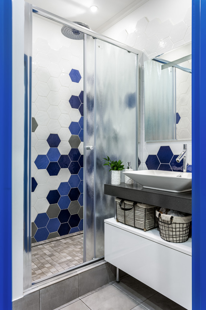 Idéer för ett litet skandinaviskt badrum med dusch, med blå kakel, vit kakel, keramikplattor, bänkskiva i akrylsten, dusch med skjutdörr, släta luckor, vita skåp, en dusch i en alkov, ett fristående handfat och grått golv