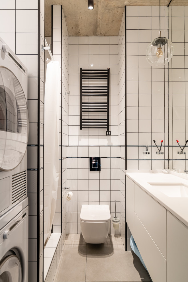 Exempel på ett skandinaviskt vit vitt badrum med dusch, med släta luckor, vita skåp, en dusch i en alkov, en vägghängd toalettstol, vit kakel, ett undermonterad handfat, grått golv och dusch med duschdraperi