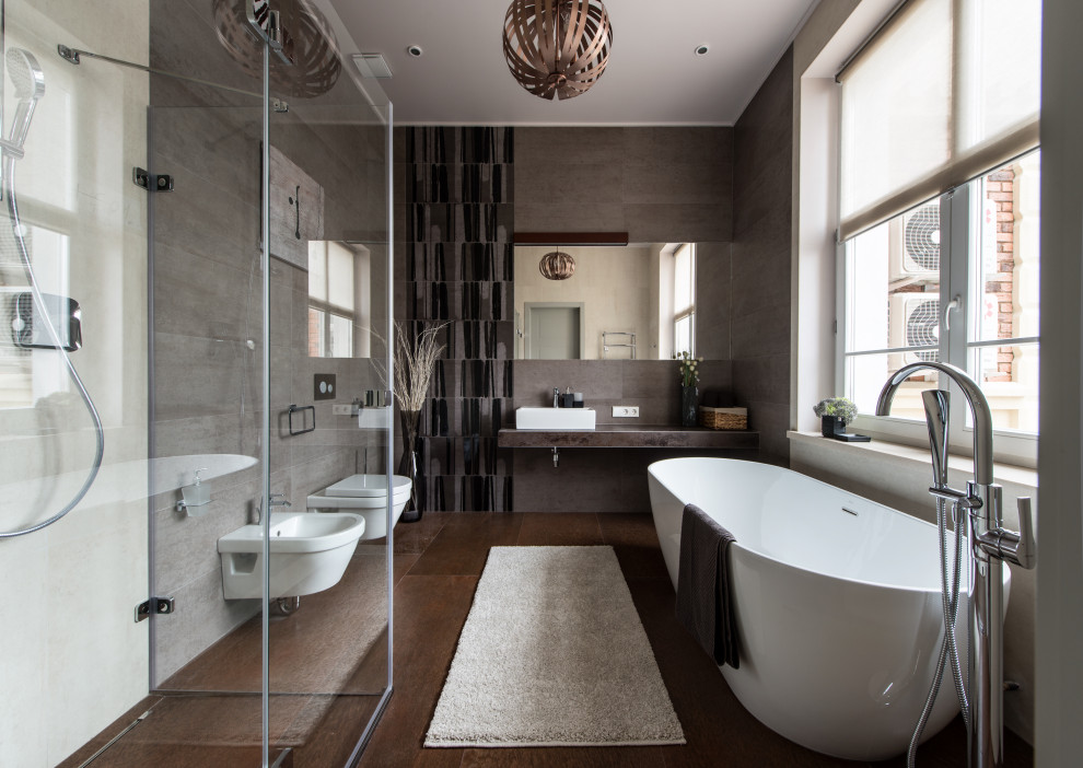 Inspiration pour une salle de bain principale design avec une baignoire indépendante, un bidet, une vasque et un sol marron.