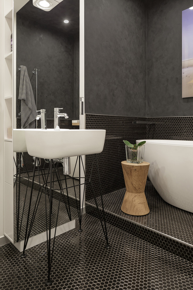 На фото: главная ванная комната в современном стиле с черными стенами, полом из керамической плитки, черным полом, отдельно стоящей ванной, черной плиткой, плиткой мозаикой и консольной раковиной