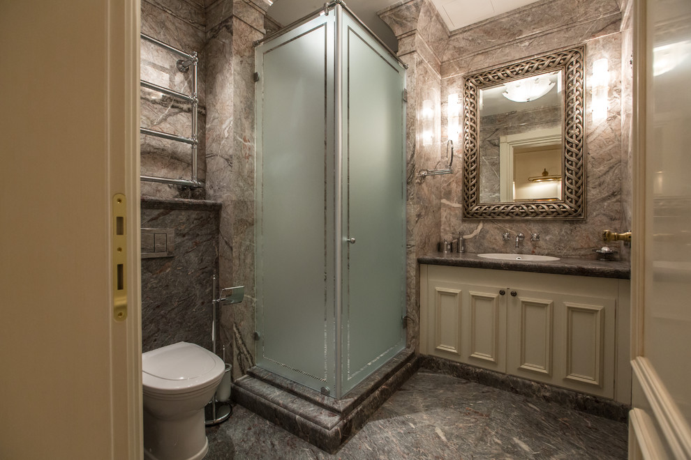 Exempel på ett stort klassiskt badrum med dusch, med luckor med upphöjd panel, beige skåp, en hörndusch, en toalettstol med separat cisternkåpa, grå kakel, marmorkakel, grå väggar, marmorgolv, ett undermonterad handfat, marmorbänkskiva, grått golv och dusch med gångjärnsdörr