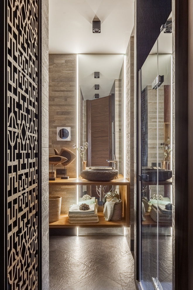 Idée de décoration pour une petite salle de bain design avec un carrelage gris, des carreaux de porcelaine, un sol en carrelage de porcelaine, un sol noir, une cabine de douche à porte battante, un placard sans porte et une vasque.