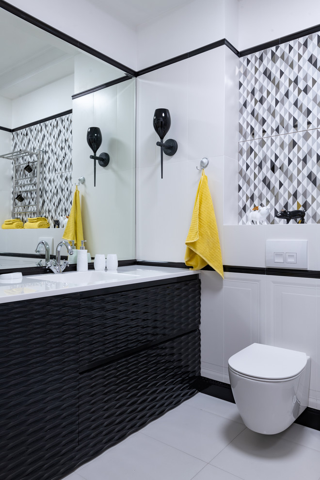 Photo of a scandi bathroom in Moscow with black cabinets, a submerged bath, a wall mounted toilet, black and white tiles, ceramic tiles, white walls, ceramic flooring, an integrated sink and white floors.
