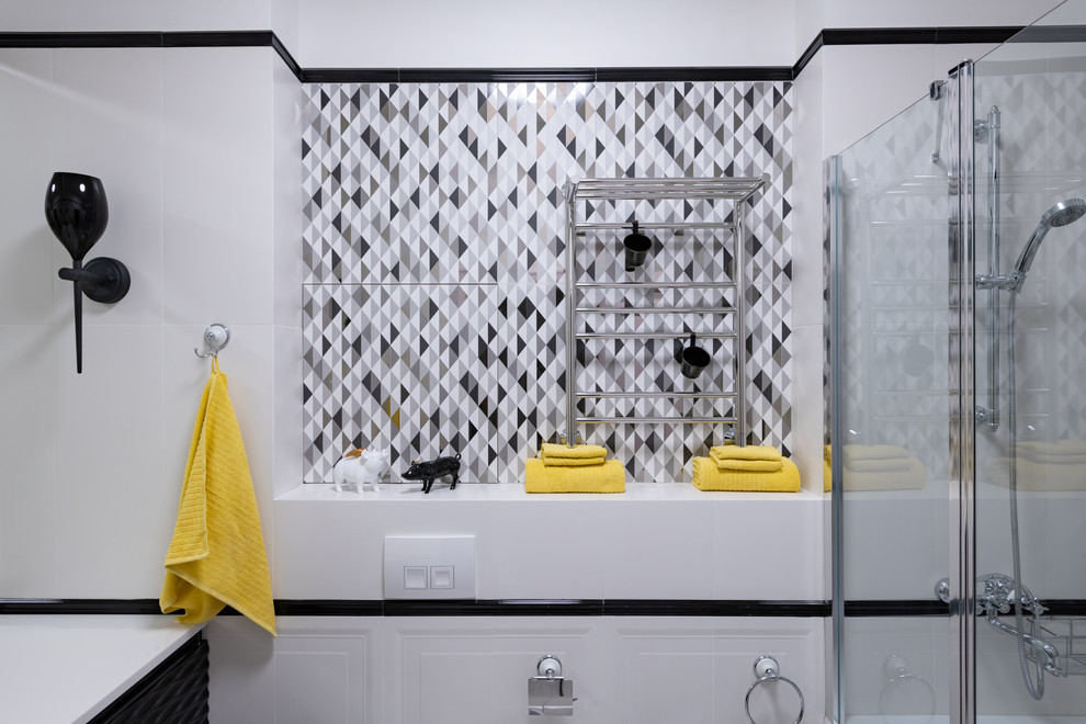 Cette image montre une salle de bain traditionnelle avec des portes de placard noires, une baignoire encastrée, WC suspendus, un carrelage noir et blanc, des carreaux de céramique, un mur blanc, un sol en carrelage de céramique, un lavabo intégré, un sol blanc et un plan de toilette blanc.