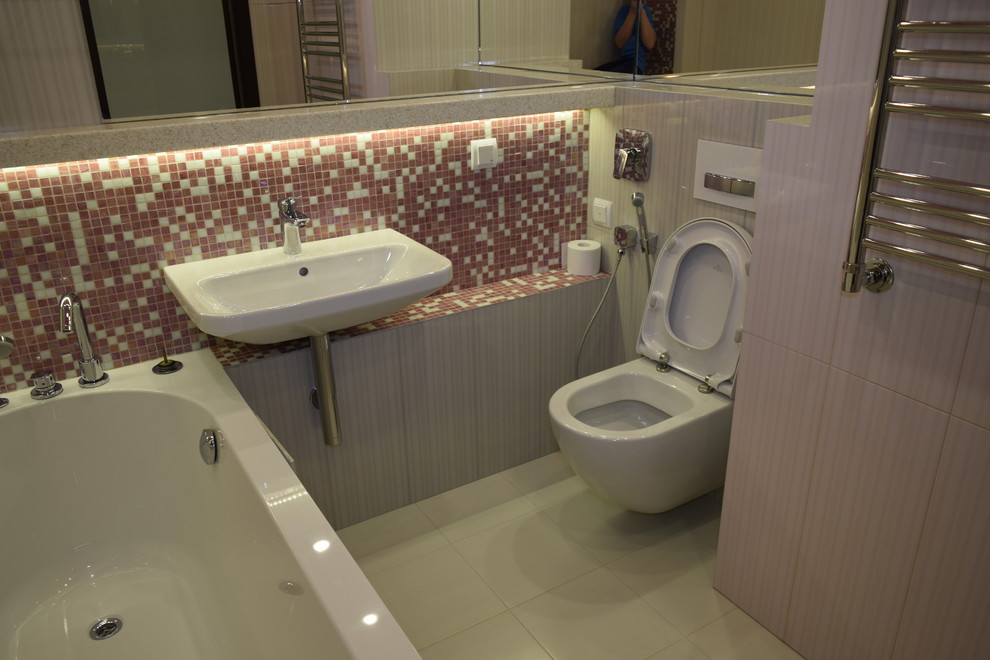Пример оригинального дизайна: большая главная ванная комната в стиле неоклассика (современная классика) с полновстраиваемой ванной, инсталляцией, розовой плиткой, керамической плиткой, бежевыми стенами, полом из керамической плитки, подвесной раковиной, мраморной столешницей, розовым полом, открытым душем и бежевой столешницей