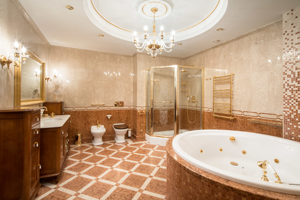 Klassisk inredning av ett stort en-suite badrum, med en jacuzzi, en hörndusch, en bidé, beige kakel, marmorgolv, marmorbänkskiva, skåp i mellenmörkt trä, ett undermonterad handfat och dusch med gångjärnsdörr