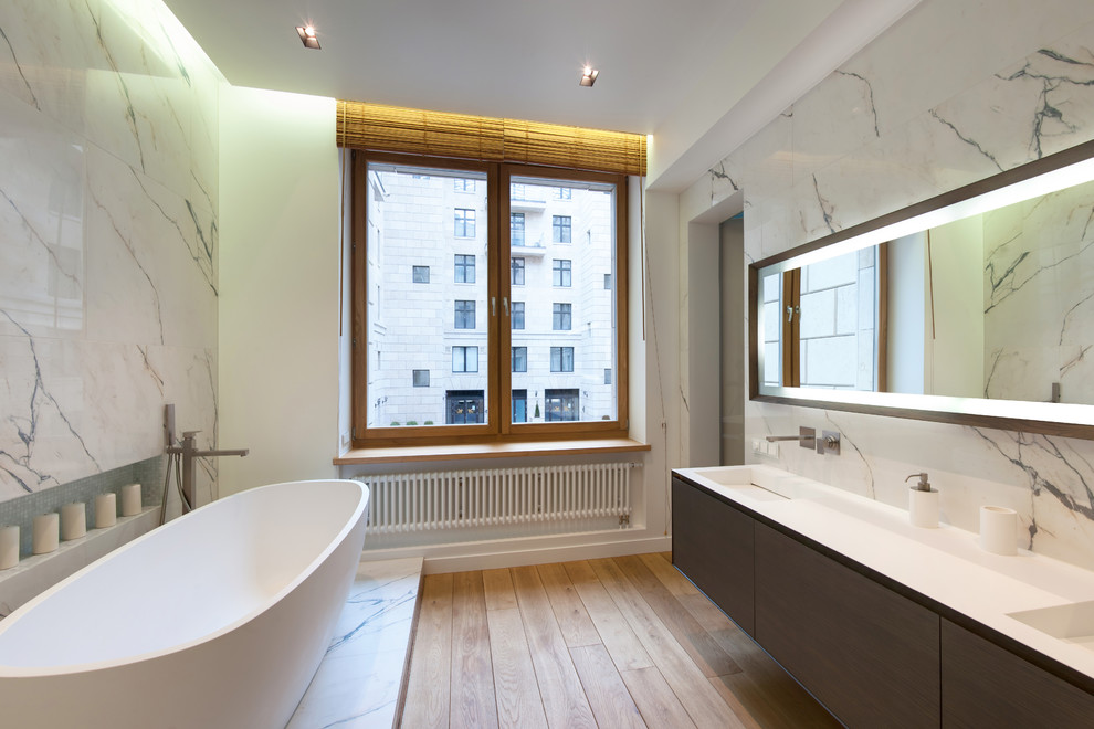 На фото: ванная комната в современном стиле с плоскими фасадами, коричневыми фасадами, отдельно стоящей ванной, белыми стенами, светлым паркетным полом, монолитной раковиной, бежевым полом и белой столешницей с