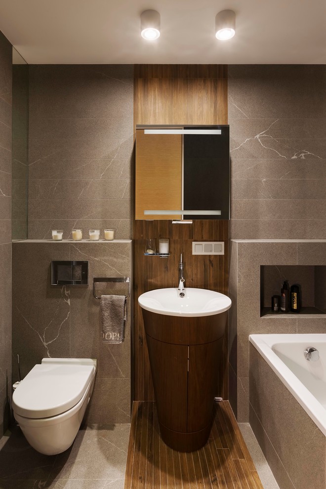 Diseño de cuarto de baño principal actual con bañera empotrada, combinación de ducha y bañera, sanitario de pared, baldosas y/o azulejos grises y lavabo con pedestal