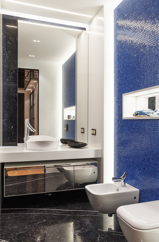 На фото: детская ванная комната в современном стиле с стеклянными фасадами, синей плиткой, плиткой мозаикой, белыми стенами, мраморным полом, черным полом, биде, настольной раковиной и белой столешницей