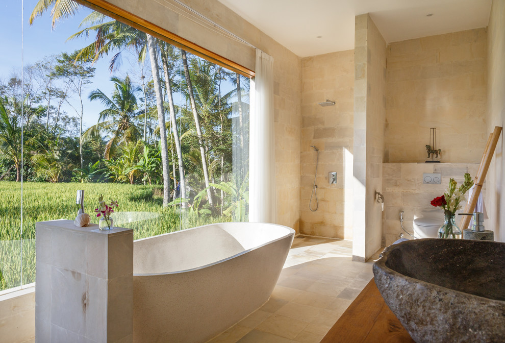 Ispirazione per una stanza da bagno tropicale con vasca freestanding, doccia a filo pavimento, pareti beige, lavabo a bacinella e doccia aperta