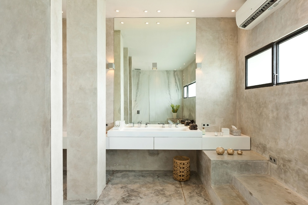 На фото: ванная комната в современном стиле с плоскими фасадами, белыми фасадами, серыми стенами, бетонным полом, раковиной с несколькими смесителями, серым полом и белой столешницей с