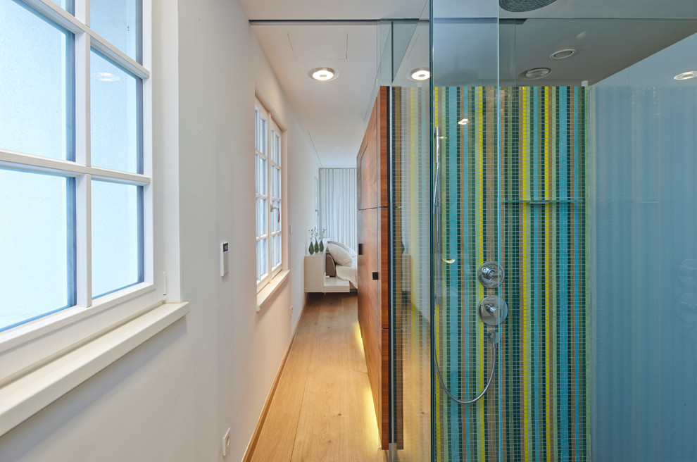 Cette photo montre une salle de bain principale tendance avec une douche d'angle, un carrelage multicolore, mosaïque, un mur blanc et parquet clair.