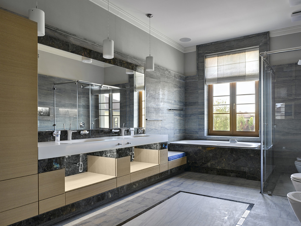 Exemple d'une salle de bain principale tendance en bois clair avec un placard à porte plane, une baignoire posée, une douche à l'italienne, un carrelage gris, un mur gris, un lavabo intégré et un sol gris.