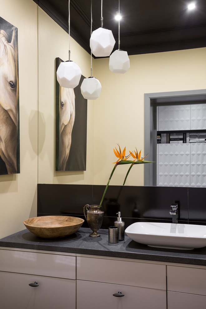 Cette photo montre une salle de bain tendance avec un placard à porte plane, des portes de placard blanches, un mur jaune et une vasque.
