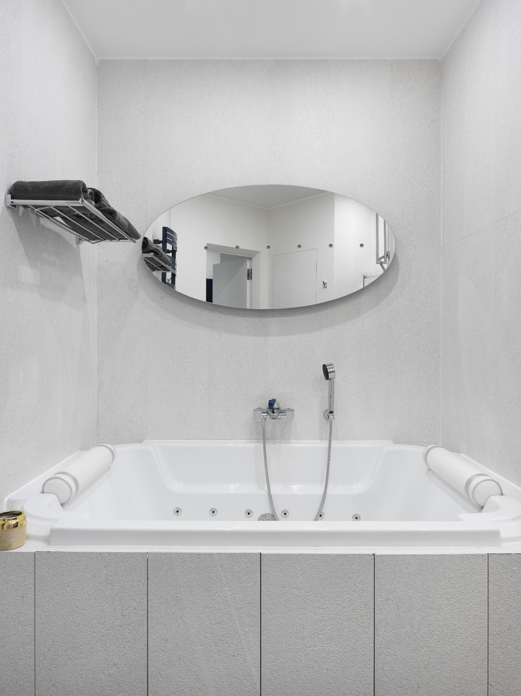 Cette image montre une salle de bain principale design avec un bain bouillonnant et un mur gris.