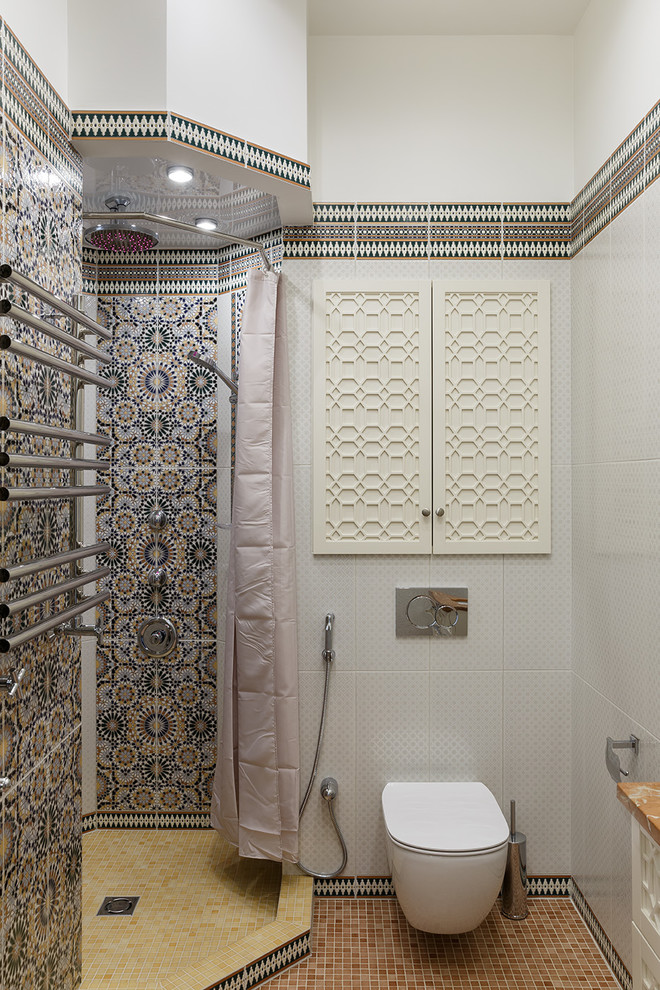 Foto på ett orientaliskt badrum med dusch, med en hörndusch, en vägghängd toalettstol, grå kakel, mosaikgolv, brunt golv och dusch med duschdraperi