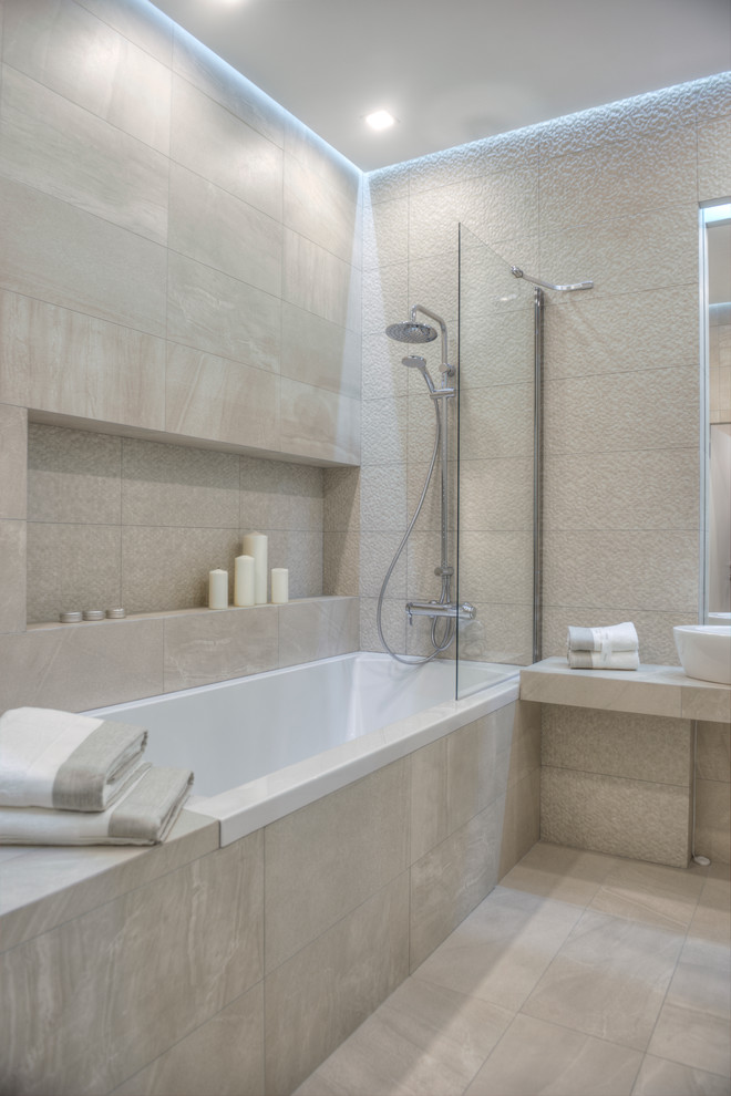 На фото: ванная комната в современном стиле с ванной в нише, душем над ванной и бежевой плиткой с