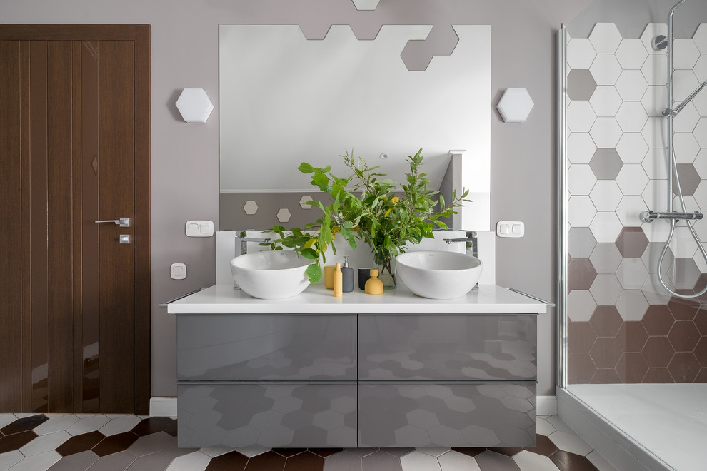 На фото: ванная комната в современном стиле с плоскими фасадами, серыми фасадами, разноцветной плиткой, серыми стенами, душевой кабиной, настольной раковиной, разноцветным полом, белой столешницей и акцентной стеной