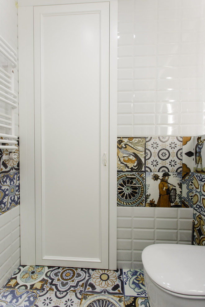This is an example of a small eclectic ensuite bathroom in Saint Petersburg with flat-panel cabinets, blue cabinets, a submerged bath, a shower/bath combination, a wall mounted toilet, multi-coloured tiles, ceramic tiles, multi-coloured walls, ceramic flooring, a wall-mounted sink, engineered stone worktops, multi-coloured floors, a shower curtain and white worktops.