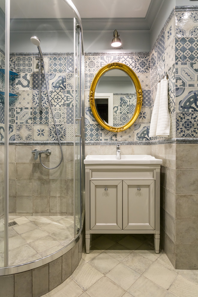 На фото: ванная комната в классическом стиле с фасадами с утопленной филенкой, бежевыми фасадами, угловым душем, синей плиткой, бежевой плиткой, душевой кабиной, монолитной раковиной и душем с раздвижными дверями с