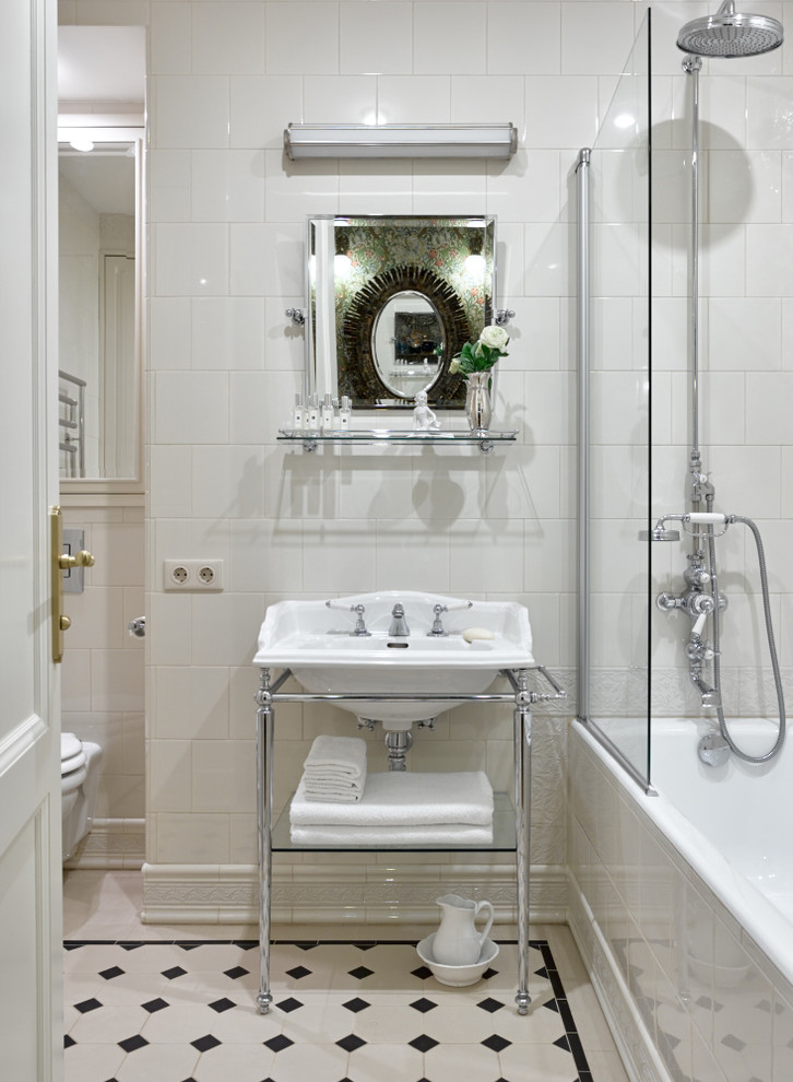 Klassisk inredning av ett en-suite badrum, med öppna hyllor, ett badkar i en alkov, en dusch/badkar-kombination, en vägghängd toalettstol, vit kakel och ett konsol handfat