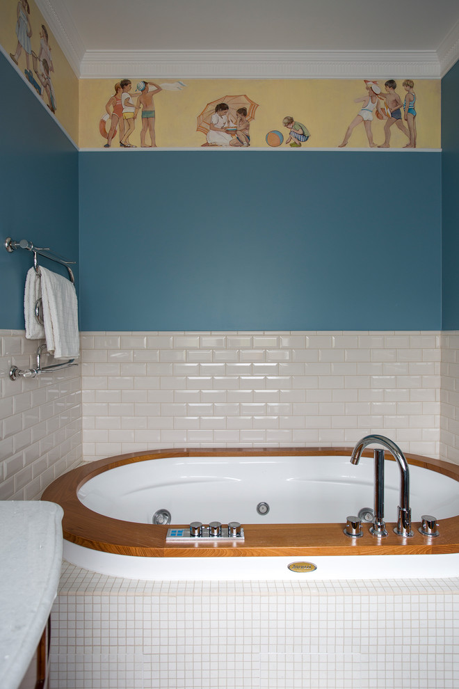 Пример оригинального дизайна: большая детская ванная комната в стиле неоклассика (современная классика) с гидромассажной ванной, белой плиткой, плиткой кабанчик, синими стенами, фасадами с утопленной филенкой, фасадами цвета дерева среднего тона, душем в нише, полом из керамической плитки, врезной раковиной, мраморной столешницей, разноцветным полом, душем с раздвижными дверями и инсталляцией