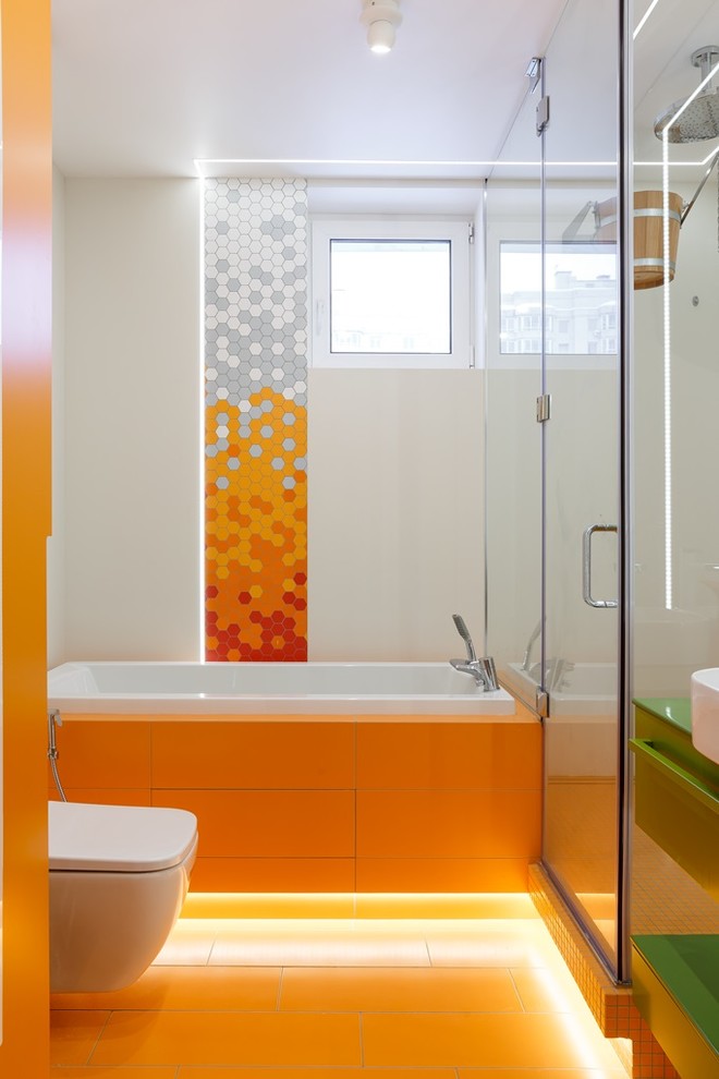 Aménagement d'une salle de bain principale contemporaine avec un placard à porte plane, des portes de placards vertess, une baignoire en alcôve, une douche d'angle, WC suspendus, un carrelage orange, un mur blanc, une vasque, un sol orange et une cabine de douche à porte battante.