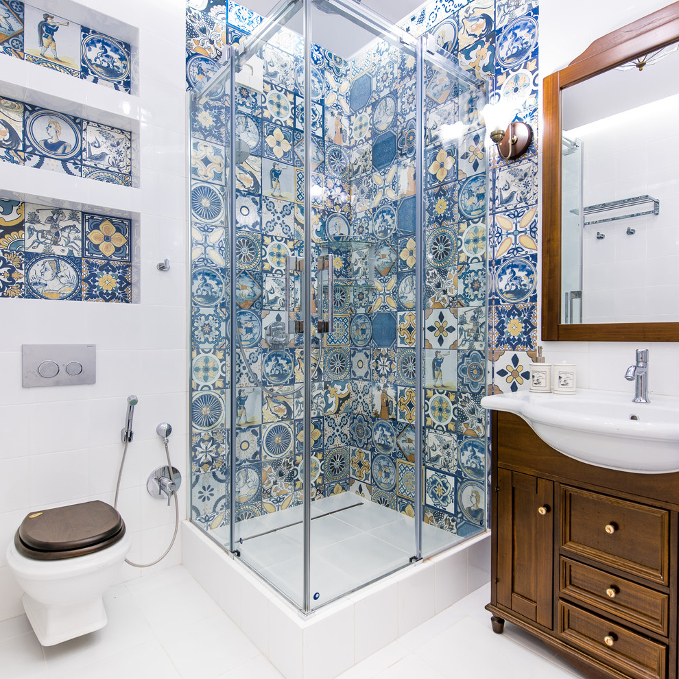 Cette photo montre une salle d'eau chic en bois foncé avec une douche d'angle, WC suspendus, un carrelage bleu, un carrelage blanc, un sol blanc, une cabine de douche à porte coulissante, un plan vasque et un placard avec porte à panneau encastré.