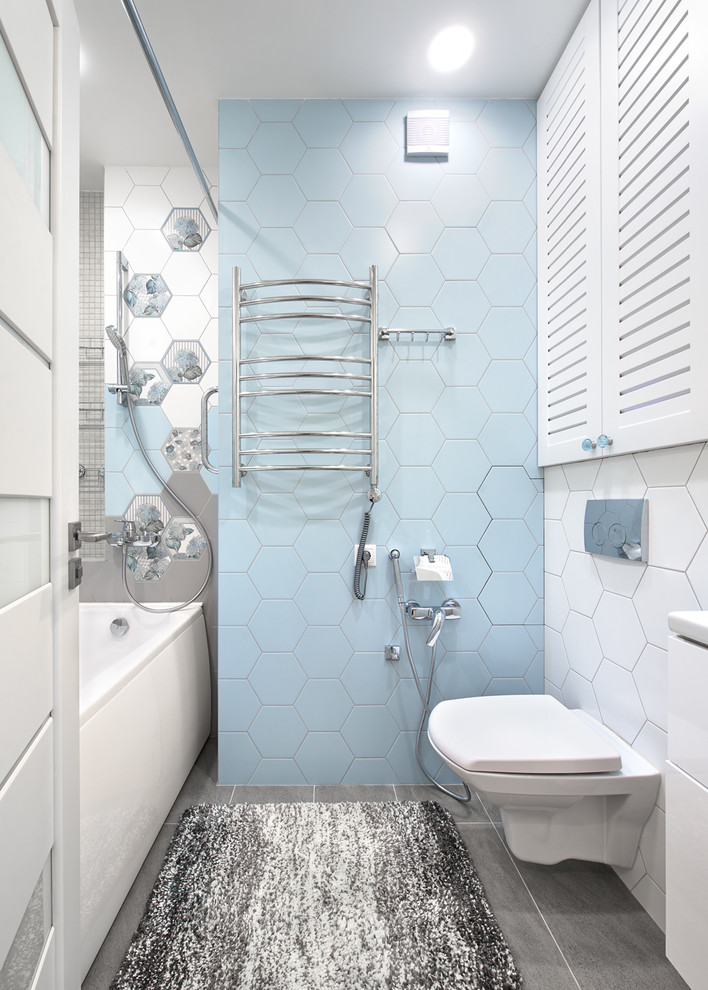 Idee per una stanza da bagno padronale design con ante lisce, ante bianche, vasca ad alcova, WC sospeso, piastrelle blu, piastrelle bianche, pavimento grigio e doccia con tenda