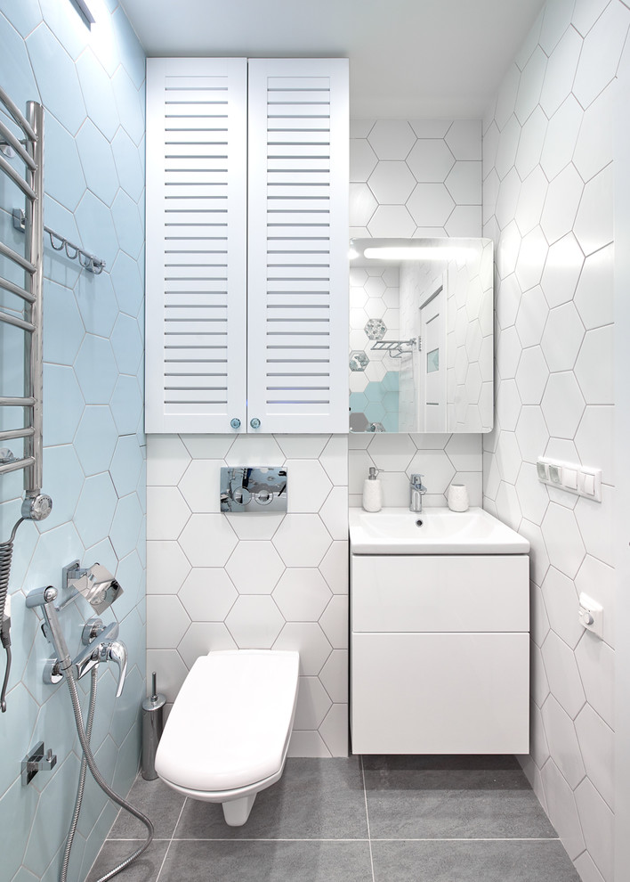 Пример оригинального дизайна: ванная комната в современном стиле с плоскими фасадами, белыми фасадами, инсталляцией, синей плиткой, белой плиткой, монолитной раковиной и серым полом