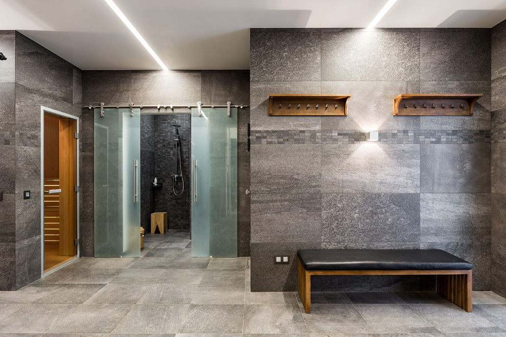На фото: баня и сауна среднего размера в современном стиле с душевой комнатой, серой плиткой, керамогранитной плиткой, серыми стенами, полом из керамогранита, серым полом и душем с раздвижными дверями с