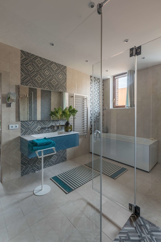 Idéer för funkis en-suite badrum, med släta luckor, blå skåp, blå kakel, beige kakel, ett integrerad handfat, beiget golv och dusch med gångjärnsdörr
