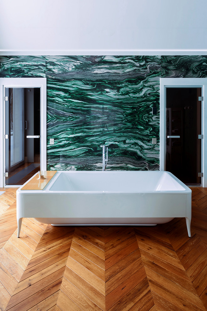 На фото: главная ванная комната в современном стиле с ванной на ножках, зелеными стенами и паркетным полом среднего тона с