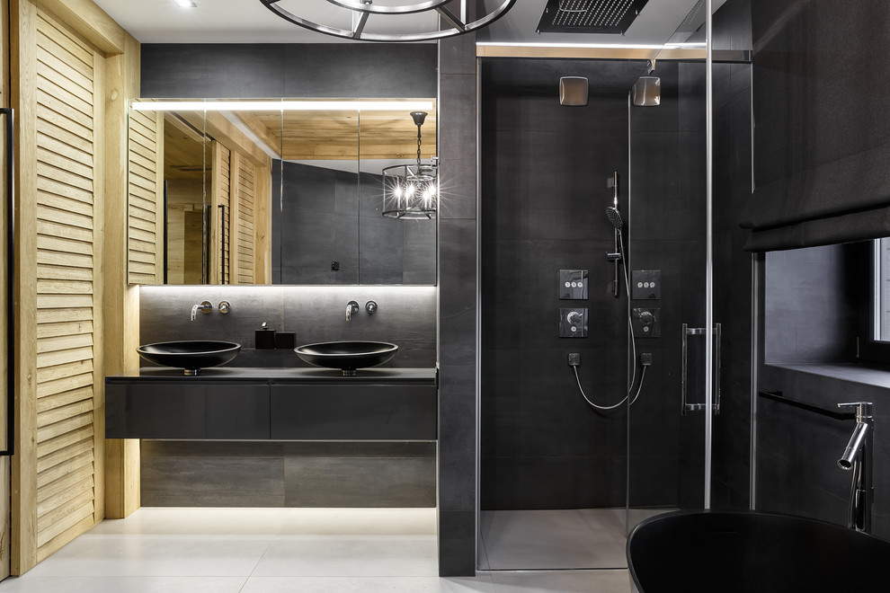 サンクトペテルブルクにあるインダストリアルスタイルのおしゃれなマスターバスルーム (フラットパネル扉のキャビネット、グレーのキャビネット、アルコーブ型シャワー、グレーのタイル、白い床、開き戸のシャワー、黒い洗面カウンター) の写真