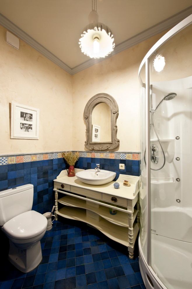На фото: ванная комната в средиземноморском стиле с белыми фасадами, угловым душем, белой плиткой, синей плиткой, душевой кабиной, настольной раковиной, унитазом-моноблоком, полом из керамической плитки и разноцветными стенами с