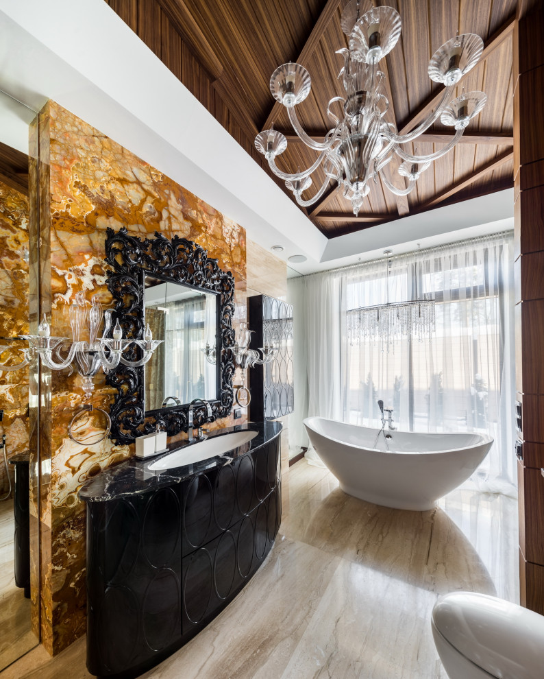 Foto på ett stort funkis svart en-suite badrum, med svarta skåp, ett fristående badkar, beige väggar, ett undermonterad handfat, beiget golv och släta luckor
