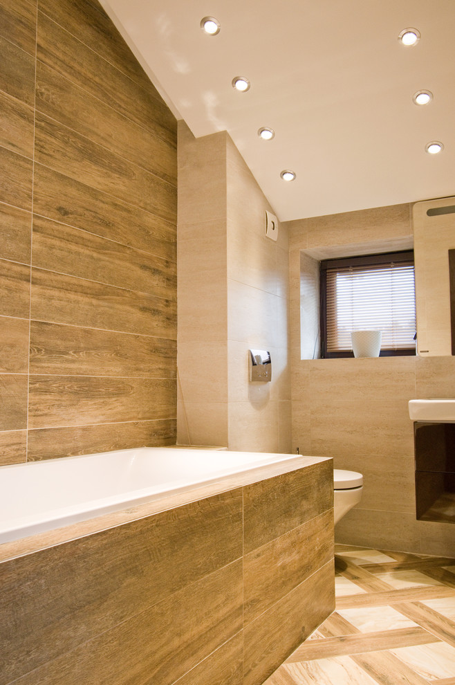 Стильный дизайн: главная ванная комната среднего размера в стиле кантри с полновстраиваемой ванной, душем над ванной, инсталляцией, коричневой плиткой, керамогранитной плиткой, бежевыми стенами, полом из керамогранита, подвесной раковиной, бежевым полом и открытым душем - последний тренд