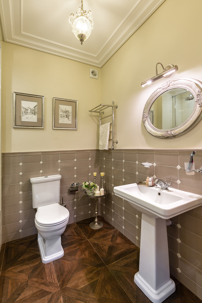 На фото: ванная комната в классическом стиле с раздельным унитазом, серой плиткой, бежевыми стенами и раковиной с пьедесталом с