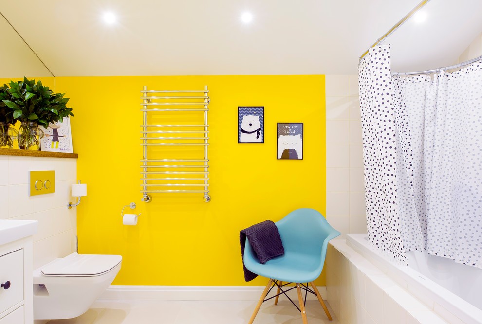 Cette image montre une grande salle d'eau design avec un placard à porte plane, des portes de placard blanches, une baignoire d'angle, un combiné douche/baignoire, WC suspendus, un carrelage blanc, un mur jaune, un sol blanc et une cabine de douche avec un rideau.