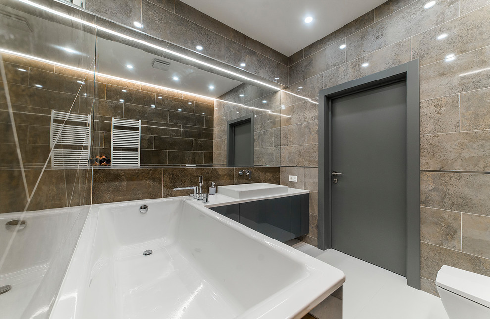 Modern inredning av ett en-suite badrum, med släta luckor, grå skåp och vitt golv
