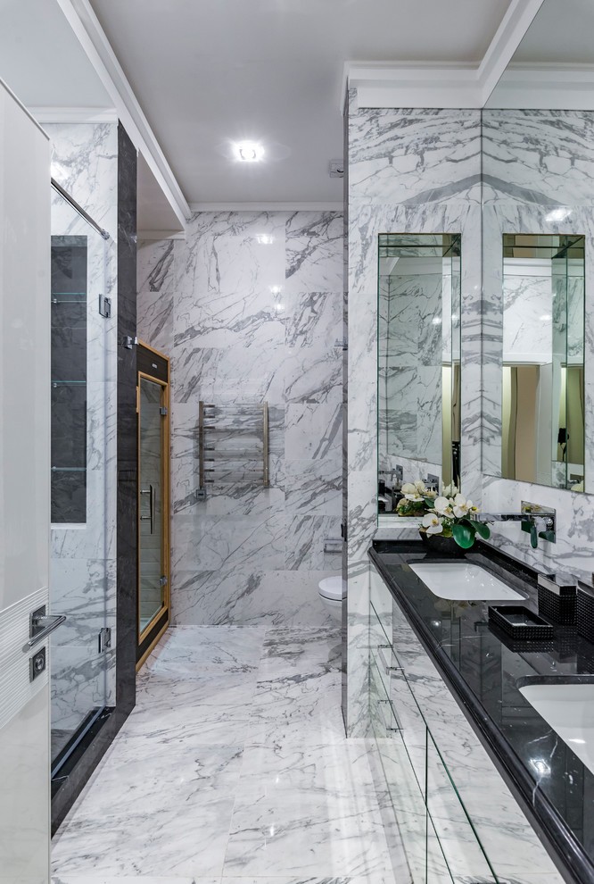 Idée de décoration pour une salle de bain design avec un placard à porte plane, WC suspendus, un carrelage blanc, un carrelage gris, un lavabo encastré, un sol gris, une cabine de douche à porte battante, un plan de toilette noir, du carrelage en marbre et un sol en marbre.