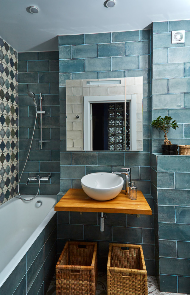 Modernes Duschbad mit Badewanne in Nische, blauen Fliesen, Aufsatzwaschbecken, Duschbadewanne, blauer Wandfarbe, Waschtisch aus Holz, offener Dusche und brauner Waschtischplatte in Sonstige