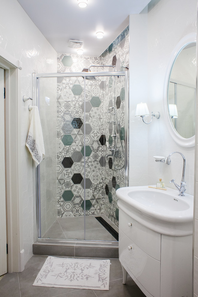 Cette image montre une petite salle de bain design avec un placard à porte plane, des portes de placard blanches, un carrelage blanc, un carrelage multicolore, des carreaux de céramique, un sol en carrelage de porcelaine, un sol gris, une cabine de douche à porte coulissante et un lavabo intégré.
