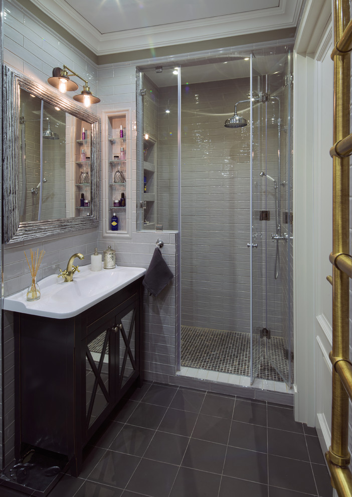 Réalisation d'une salle de bain tradition avec des portes de placard noires, un carrelage gris, un lavabo intégré et une cabine de douche à porte battante.