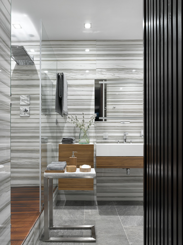 Immagine di una stanza da bagno contemporanea con ante lisce, piastrelle grigie, lavabo integrato e pavimento grigio