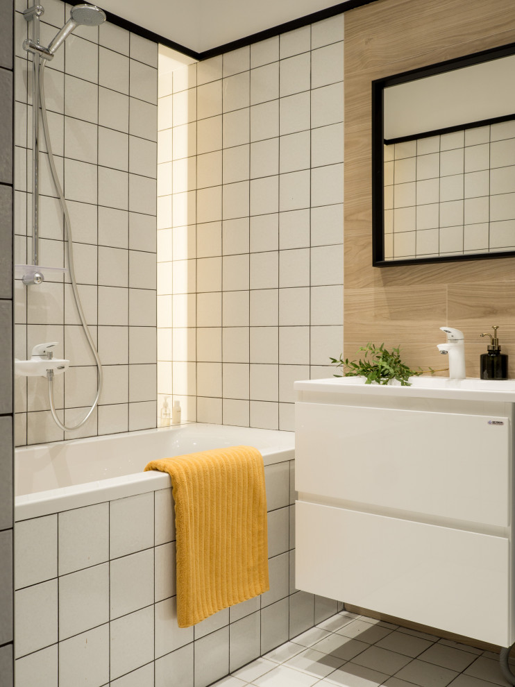 Foto på ett litet funkis en-suite badrum, med släta luckor, vita skåp, vit kakel, keramikplattor, klinkergolv i keramik, vitt golv, ett badkar i en alkov, en dusch/badkar-kombination och ett konsol handfat