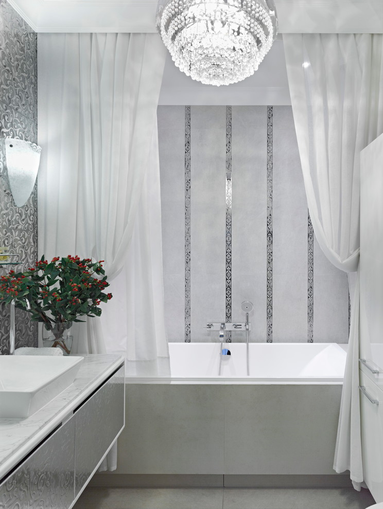 Cette photo montre une salle de bain principale chic avec un combiné douche/baignoire, un carrelage blanc, des carreaux de céramique, un mur blanc, un sol en carrelage de porcelaine, une vasque, un plan de toilette en marbre et une baignoire en alcôve.